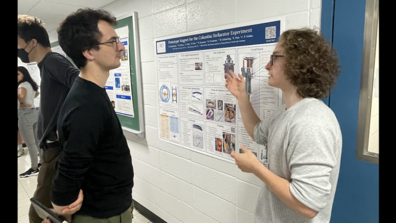 A student stands in front of a research poster