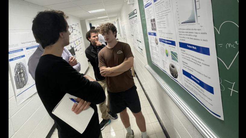 A student stands in front of a research poster