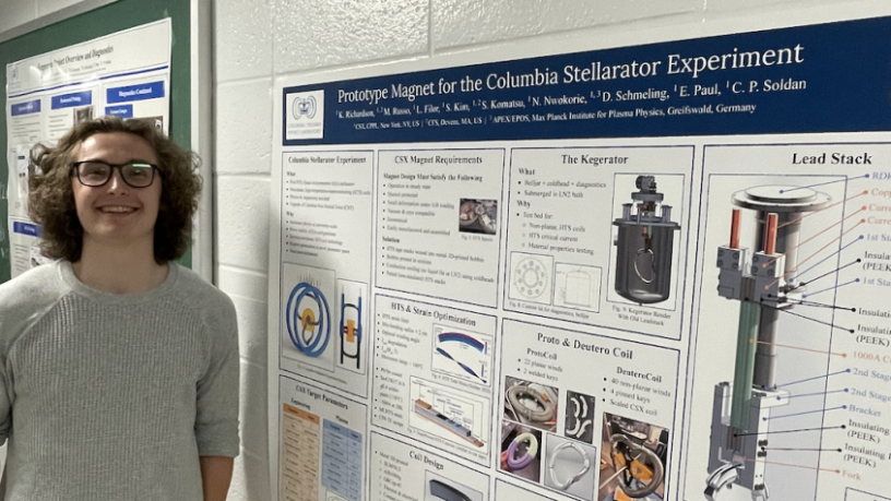 A student stands in front of a research poster