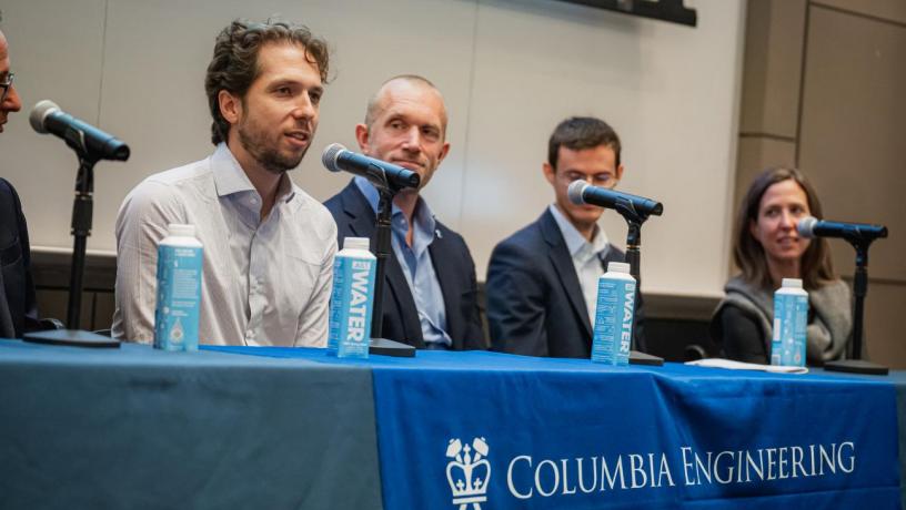 people sit at a panelist table and speak into microphones