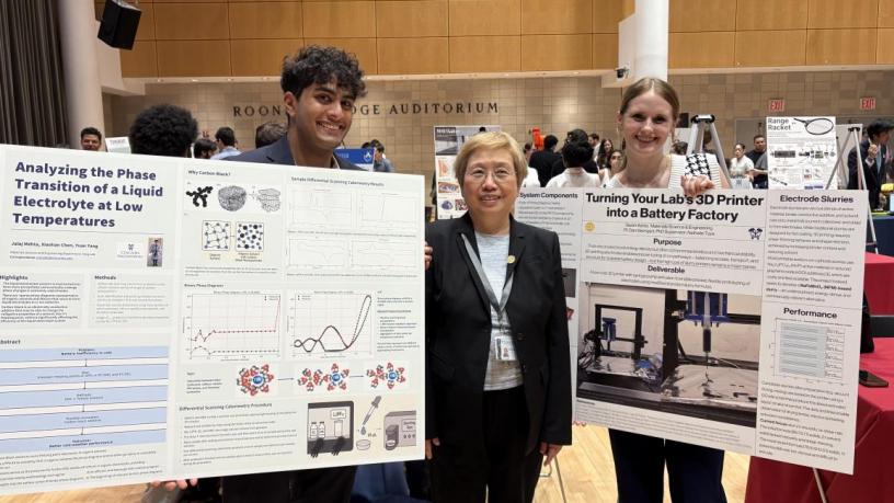 a photo of two students and a faculty member with research posters
