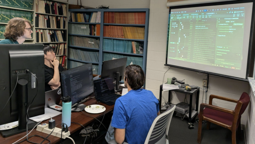 a group of students looking at computers and a projection screen