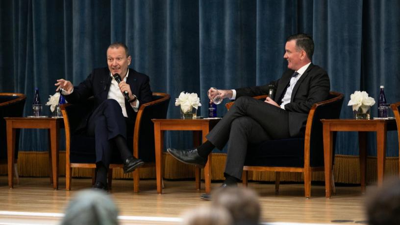 Two men in chairs sitting on a stage 