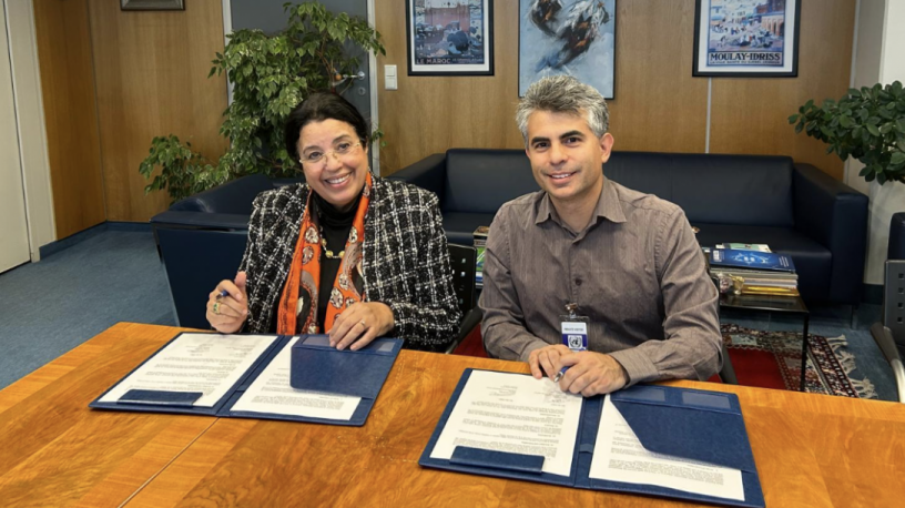 two people sit at a desk and sign documents