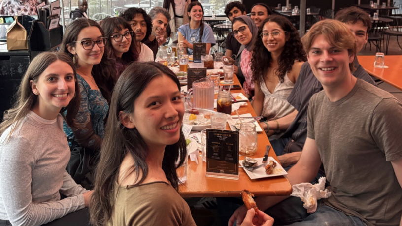 a group of college students sitting around a dining table