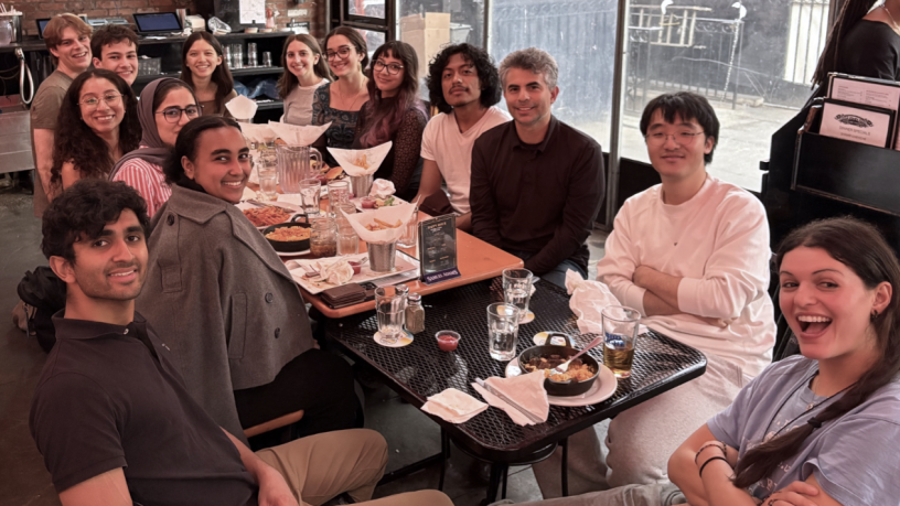a group of college students sitting around a dining table