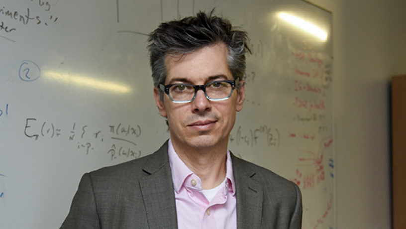 a photo of a man standing in front of a white board with math equations