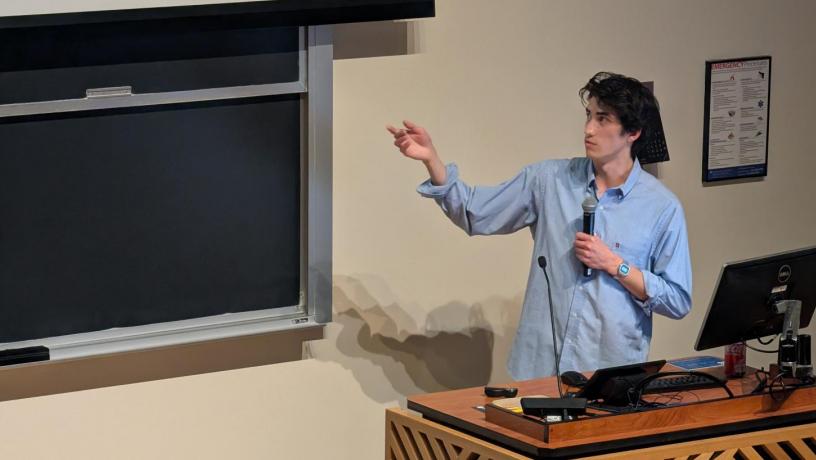 A person standing at a podium in front of a large presentation screen