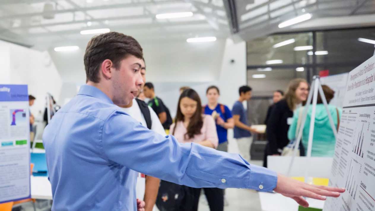 students watching a professor gesture at diagrams