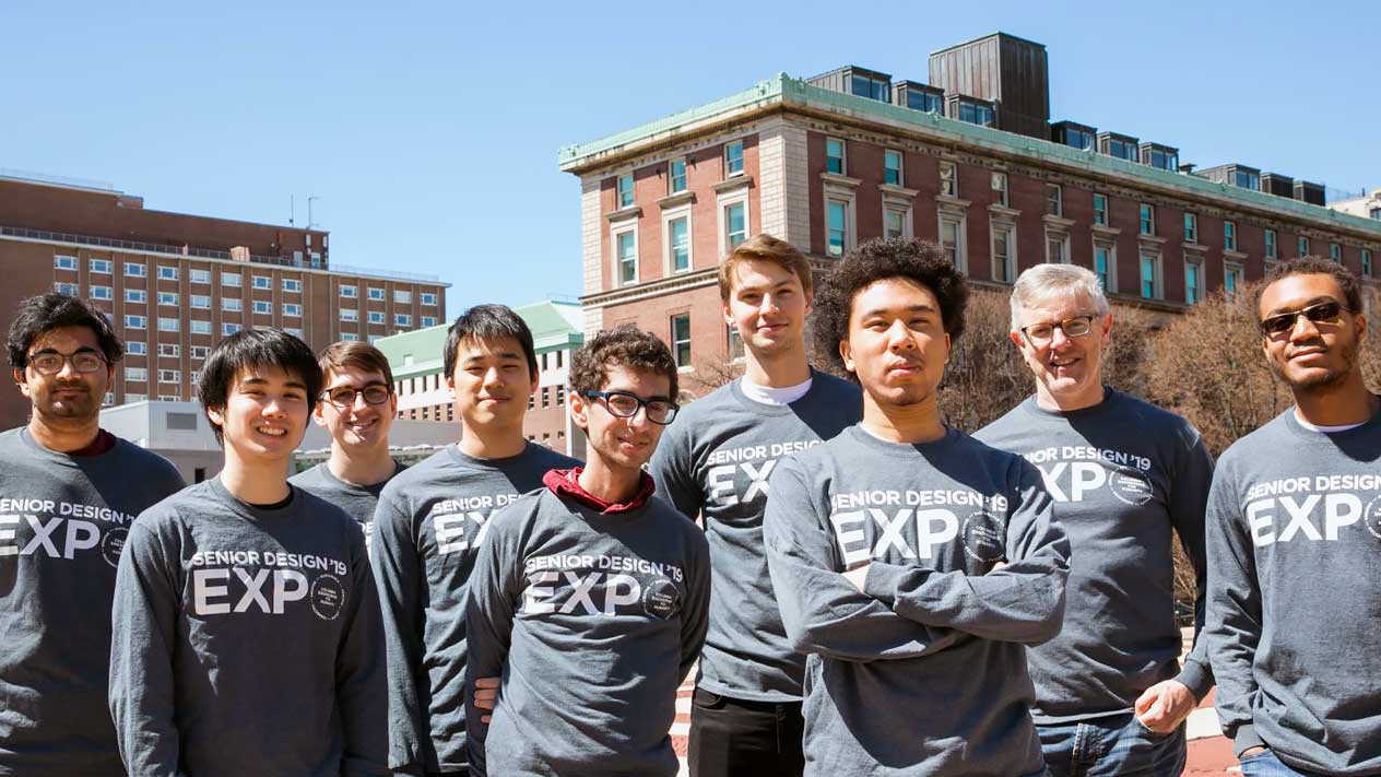 students and a professor standing outside wearing 2019 Senior Design Expo shirts