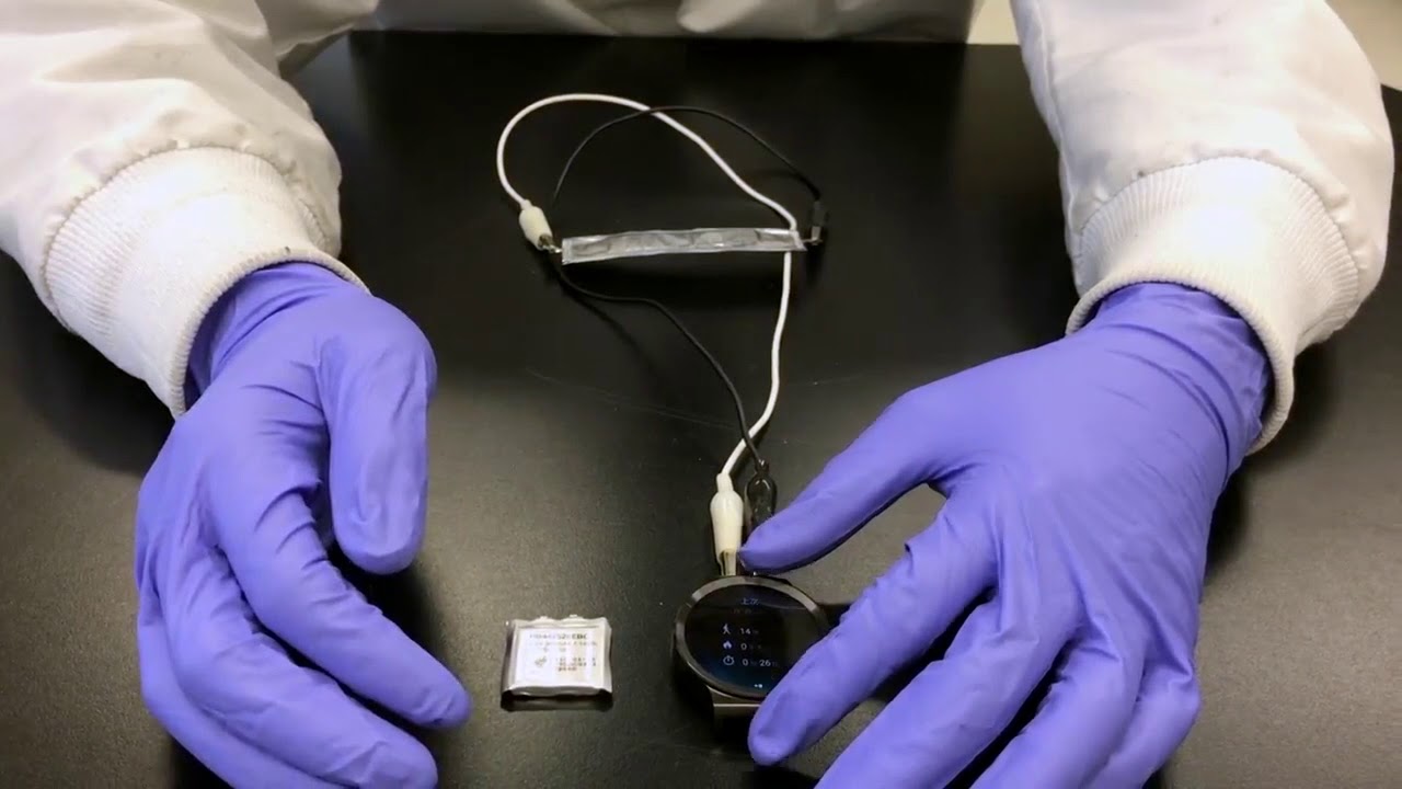 Gloved hands handling a flexible battery.