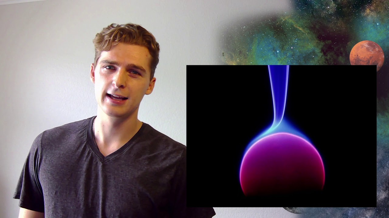 A presenter beside a glowing physics visualization.