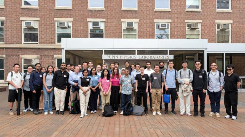 A group of people stand outside of a brick building 